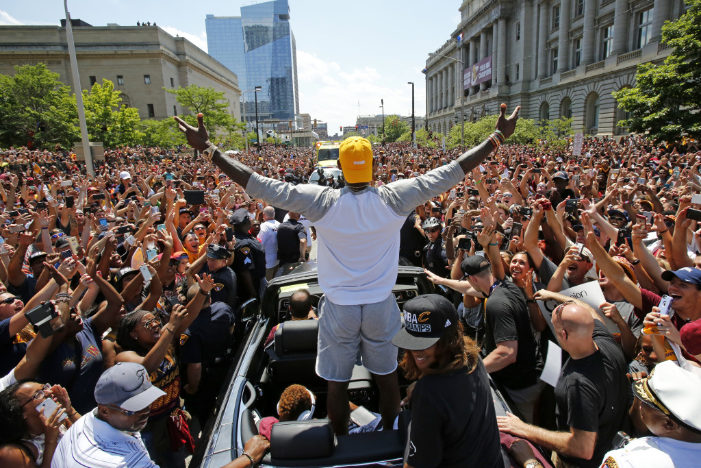Cleveland Cavaliers' LeBron James, center, stands in the back of a Rolls Royce as it makes its way through the crowd lining the parade route in downtown Cleveland, Wednesday, June 22, 2016, celebrating the basketball team's NBA championship. (AP Photo/Gene J. Puskar)