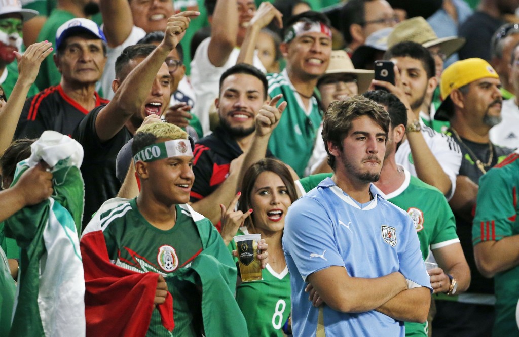 A dejected Uruguay fan, right, is surrounded by cheering Mexico fans after a third Mexico goal during the second half of a Copa America group C soccer match at University of Phoenix Stadium Sunday, June 5, 2016, in Glendale, Ariz. Mexico defeated Uruguay 3-1. (AP Photo/Ross D. Franklin)
