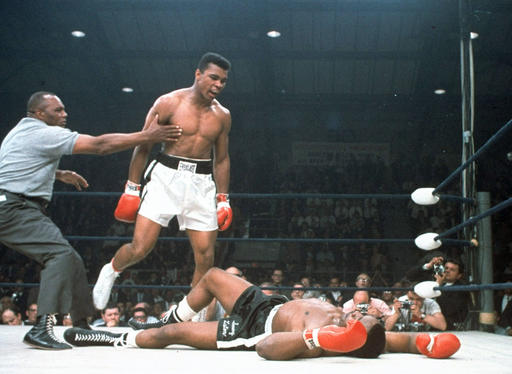 In this May 25, 1965, file photo, heavyweight champion Muhammad Ali is held back by referee Joe Walcott, left, after Ali knocked out challenger Sonny Liston in the first round of their title fight in Lewiston, Maine.  Ali, the magnificent heavyweight champion whose fast fists and irrepressible personality transcended sports and captivated the world, has died according to a statement released by his family Friday, June 3, 2016. He was 74. AP FILE PHOTO