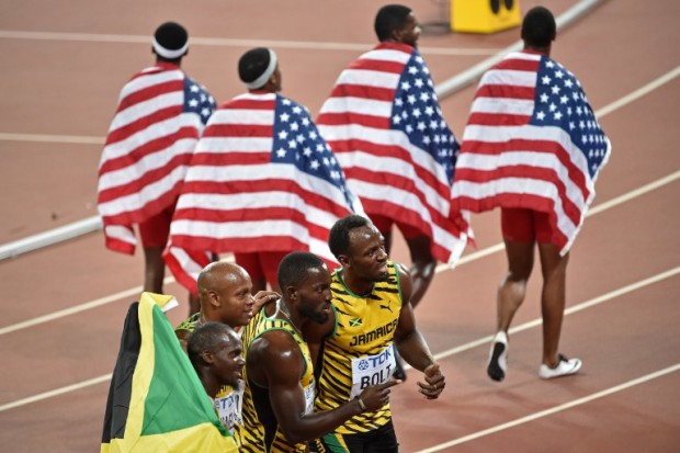 USA's relay team Tyson Gay, Mike Rodgers, Trayvon Bromell and Justin Gatlin (top) walk with national flags past Jamaica's winning team (L-R) Nesta Carter, Asafa Powell, Nickel Ashmeade and Usain Bolt at the end of the final of the men's 4x100 metres relay athletics event at the 2015 IAAF World Championships at the "Bird's Nest" National Stadium in Beijing on August 29, 2015.  The US team was disqualified.  AFP PHOTO / PEDRO UGARTE / AFP PHOTO / PEDRO UGARTE