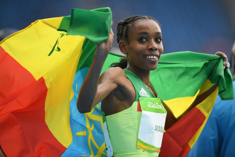 Gold medallist Ethiopia's Almaz Ayana runs with Ethiopia's national flag after the Women's 10,000m during the athletics event at the Rio 2016 Olympic Games at the Olympic Stadium in Rio de Janeiro on August 12, 2016.   / AFP PHOTO / Johannes EISELE