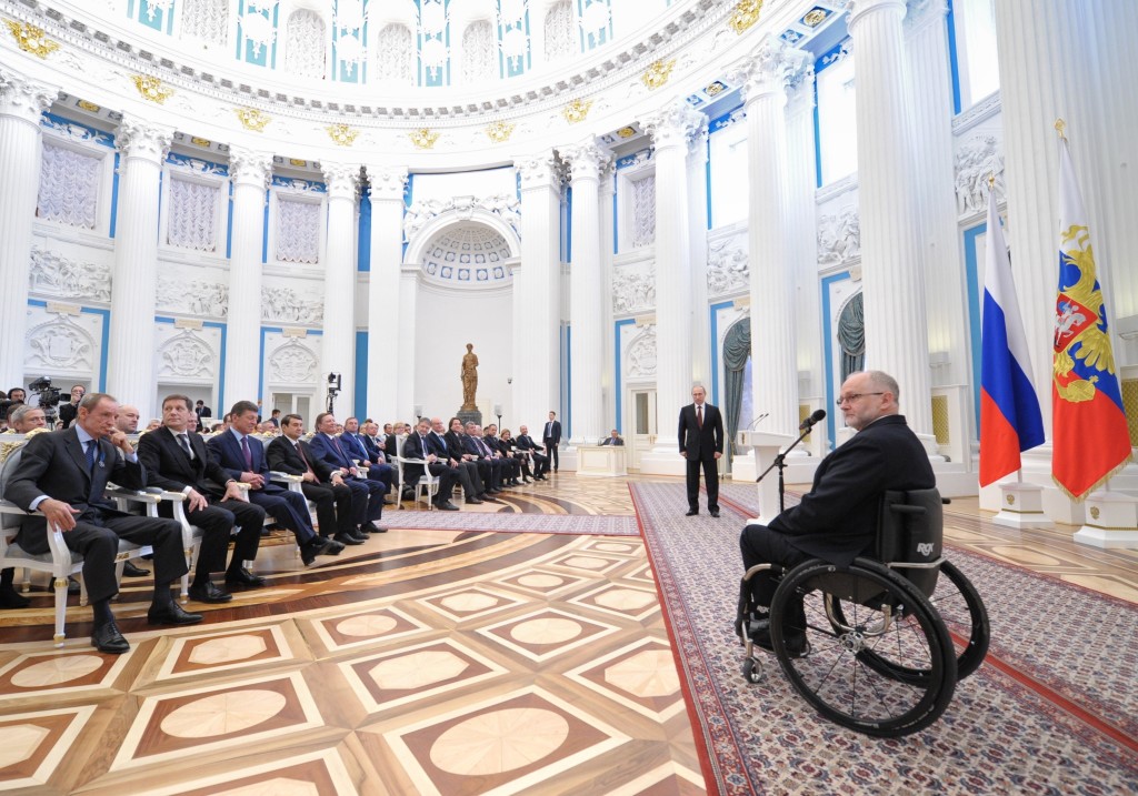 FILE - In this file photo taken on Monday, March 24, 2014, Sir Philip Craven, President of the International Paralympic Committee, right, speaks as Russian President Vladimir Putin, standing background center, listens to him during an awards ceremony in the Kremlin in Moscow, Russia. The entire Russia Paralympic team was banned Sunday Aug. 7, 2016, from competing in the Paralympic Games in September as punishment for the country's systematic doping program. (Alexei Druzhinin, Sputnik, Kremlin Pool Photo via AP, file)
