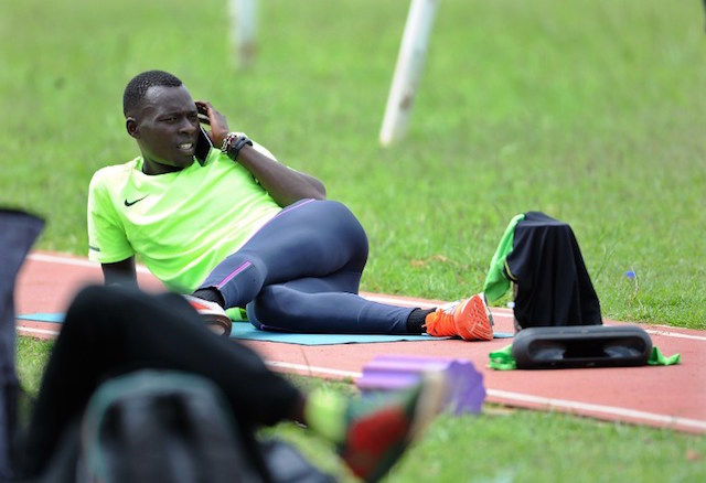 Kenyan athlete and gold medalist in the men's 400m Nicholas Bett speaks on the phone as he stretches after taking part in a track workout alongside fellow running mates July 19, 2016 at the high altitude Kipchoge Keino stadium in Eldoret. The gold medalsit at the world Championships in Beijing 2015 is part of Kenya's national team for the Rio Olympics in Brazil.  / AFP PHOTO / TONY KARUMBA