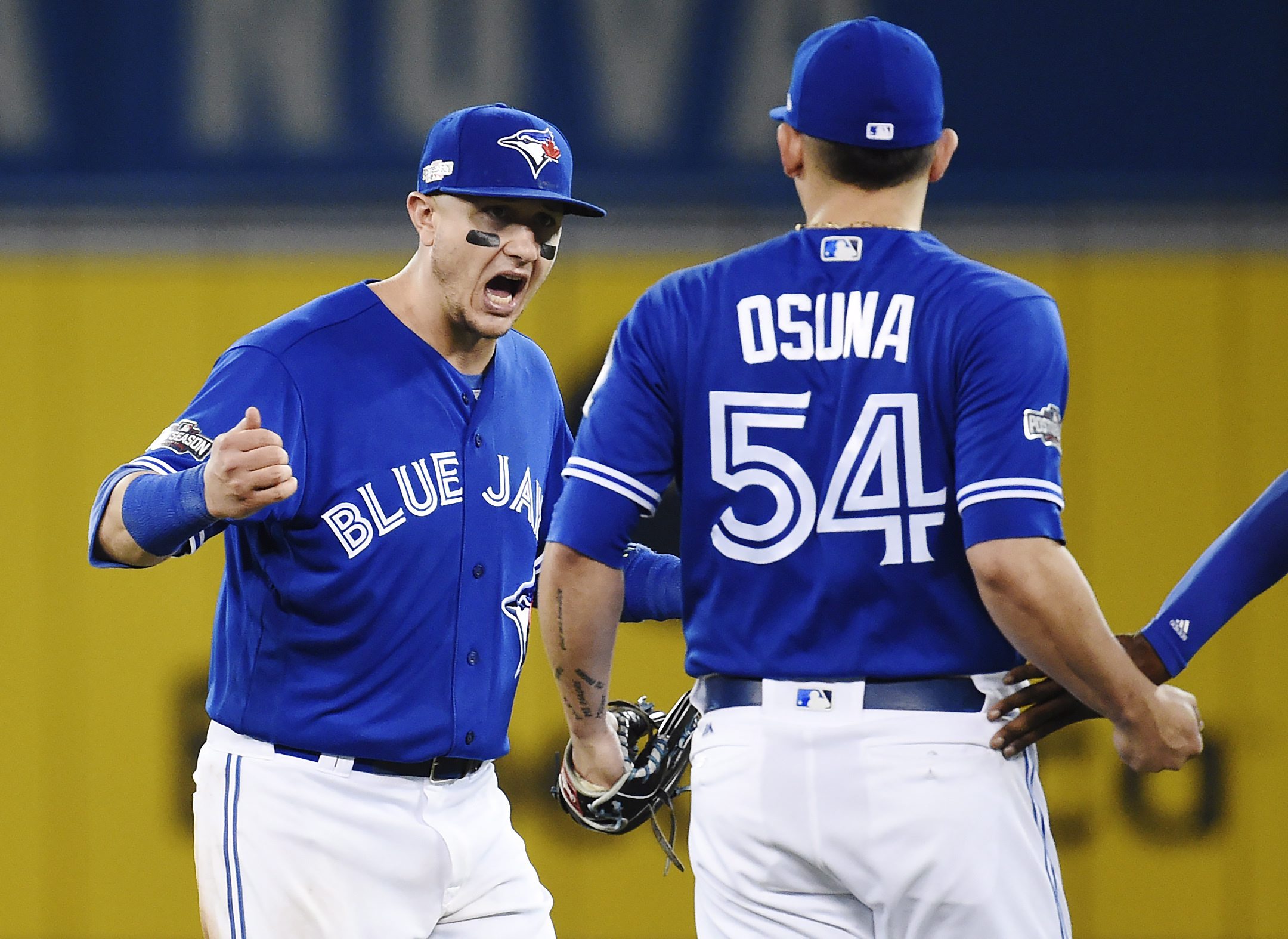 Toronto Blue Jays shortstop Troy Tulowitzki (2) and relief pitcher Roberto Osuna (54) celebrate the team's 5-1 victory over the Cleveland Indians in Game 4 of the baseball American League Championship Series, Tuesday, Oct. 18, 2016, in Toronto. (Nathan Denette/The Canadian Press via AP)