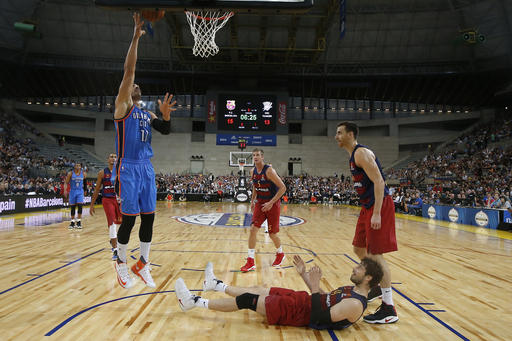 Barcelona center Ante Tomic watches from the floor as Oklahoma City Thunder center Enes Kanter jumps to the basket during a NBA Global Games basketball match between Barcelona and Oklahoma City Thunder at the Palau Sant Jordi in Barcelona. AP