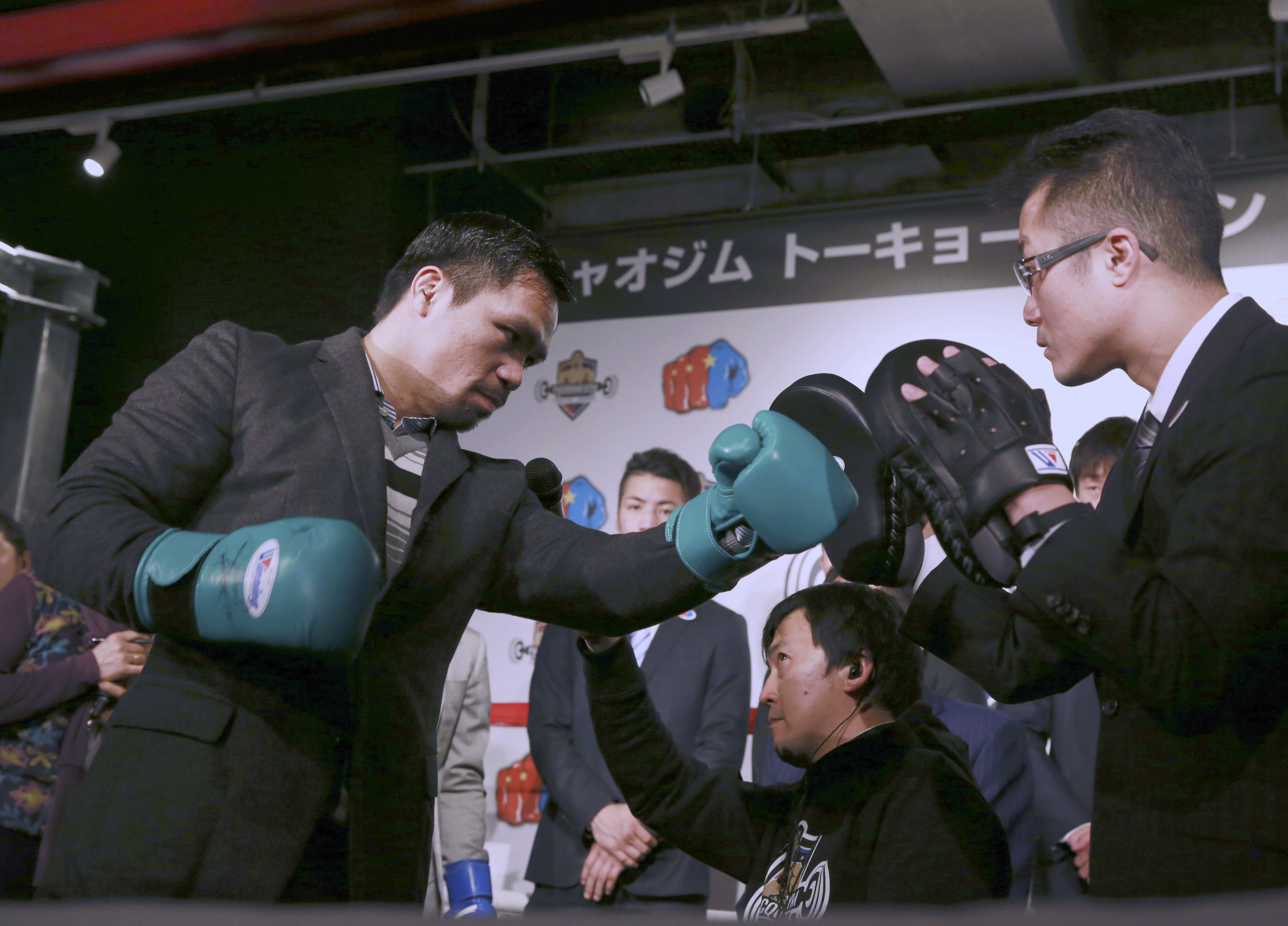Filipino boxer Manny Pacquiao, left, performs during a press conference as he launches a small boxing gym named after him in Tokyo, Friday, Nov. 25, 2016. Pacquiao says his next fight will be in April or May next year as that fits his schedule best as Philippine senator. And he would like a rematch with Floyd Mayweather Jr.  Pacquiao defeated Jessie Vargas for a welterweight title earlier in November. (AP Photo/Eugene Hoshiko)