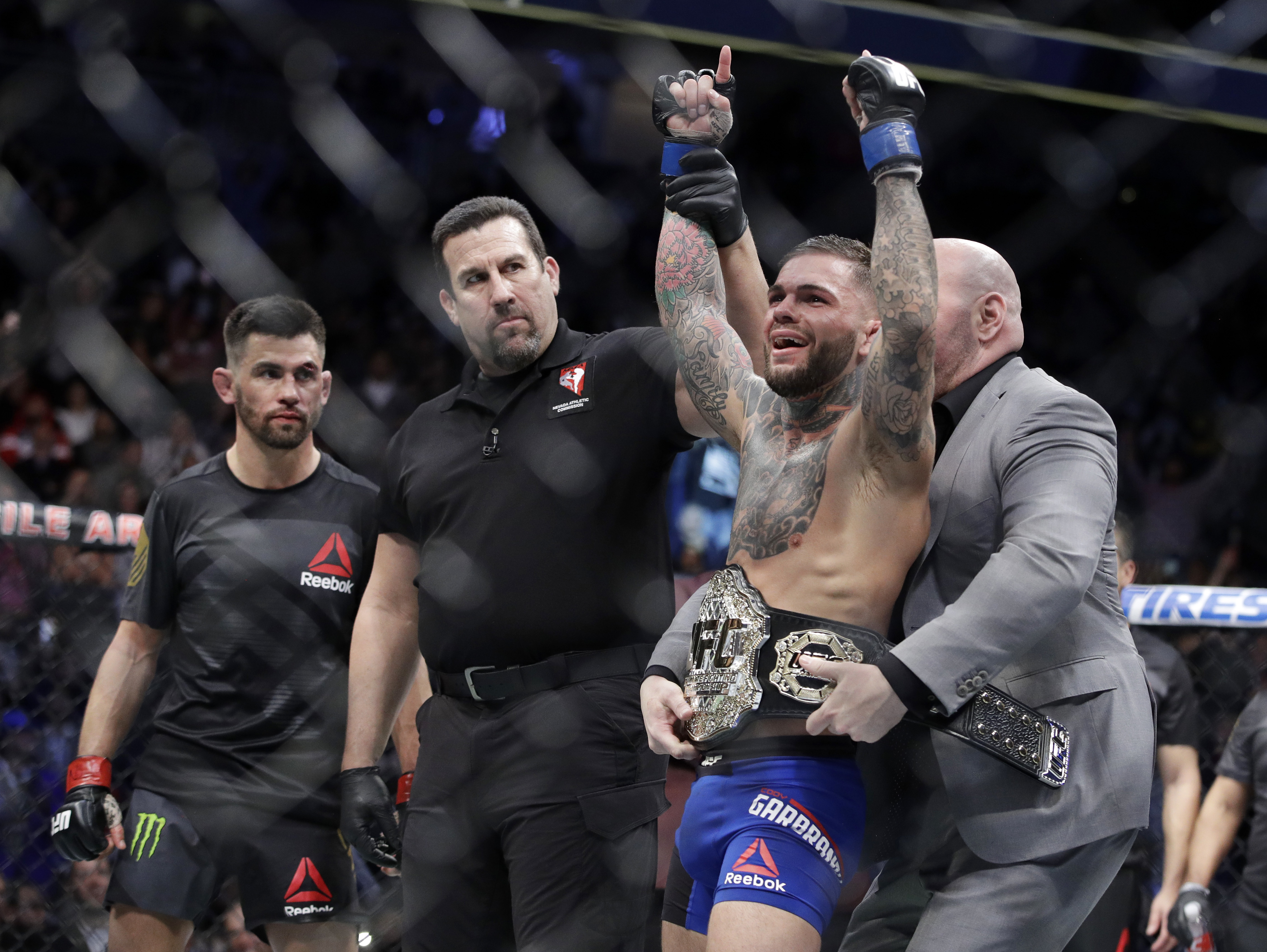 Cody Garbrandt, right, celebrates as he receives his belt after defeating Dominick Cruz, left, in a bantamweight championship mixed martial arts bout at UFC 207, Friday, Dec. 30, 2016, in Las Vegas. AP