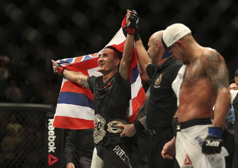 Max Holloway celebrates after defeating Anthony Pettis, right, to win the interim featherweight title during the main event of a mixed martial arts bout at UFC 206, Saturday, Dec. 10, 2016, at the Air Canada Centre in Toronto. Peter Power/The Canadian Press via AP