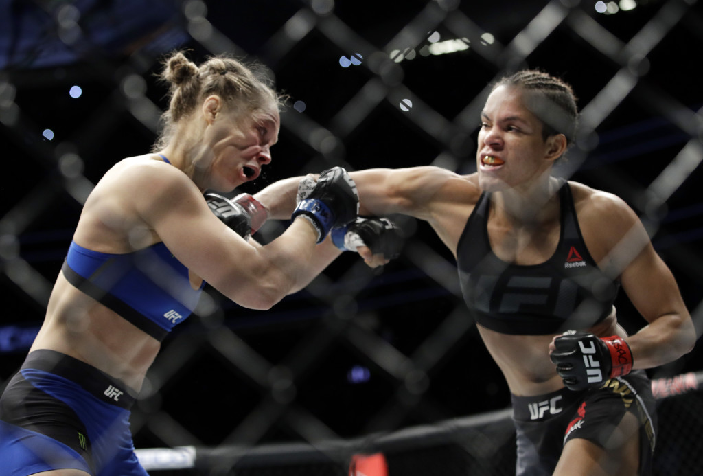 Amanda Nunes, right, connects with Ronda Rousey in the first round of their women's bantamweight championship mixed martial arts bout at UFC 207, Friday, Dec. 30, 2016, in Las Vegas. Nunes won the fight after it was stopped in the first round. (AP Photo/John Locher)