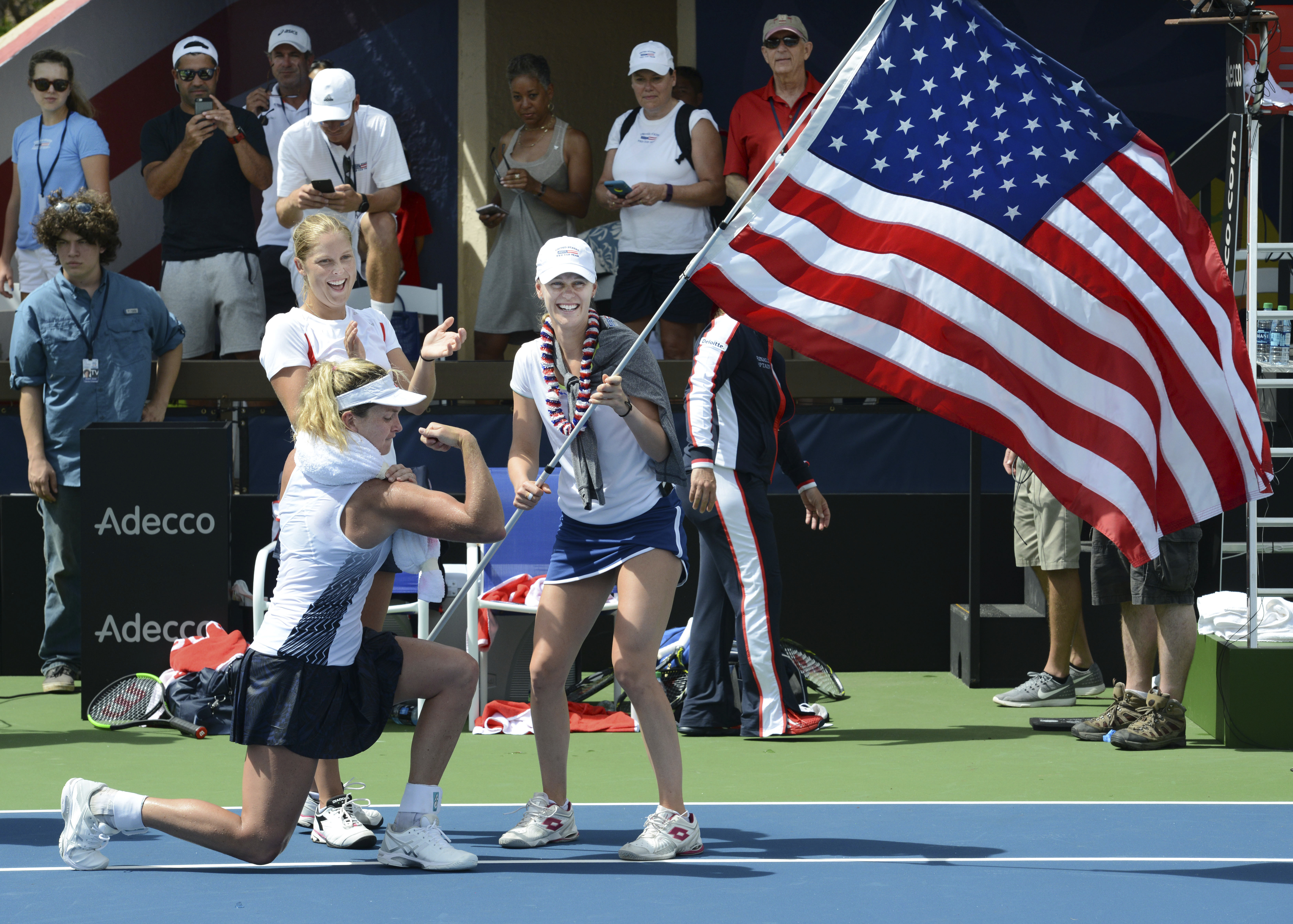 CoCo Vandeweghe flexes her muscles while celebrating with USA Fed Cup teammates Alison Riske, right, and Shelby Rogers after her singles win clinched the team victory over Germany at the Royal Lahaina Tennis Ranch in Lahaina, Hawaii on Sunday, Feb. 12, 2017. (Matthew Thayer/The Maui News via AP)