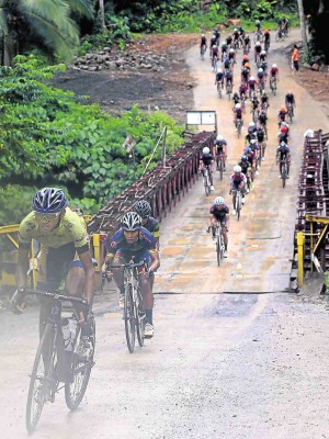 Team Go for Gold cyclist Ismael Grospe leads the peloton after crossing a makeshift bridge during Friday’s stage 8 from Daet, Camarines Norte, to Unisan, Quezon. —EDWIN BACASMAS