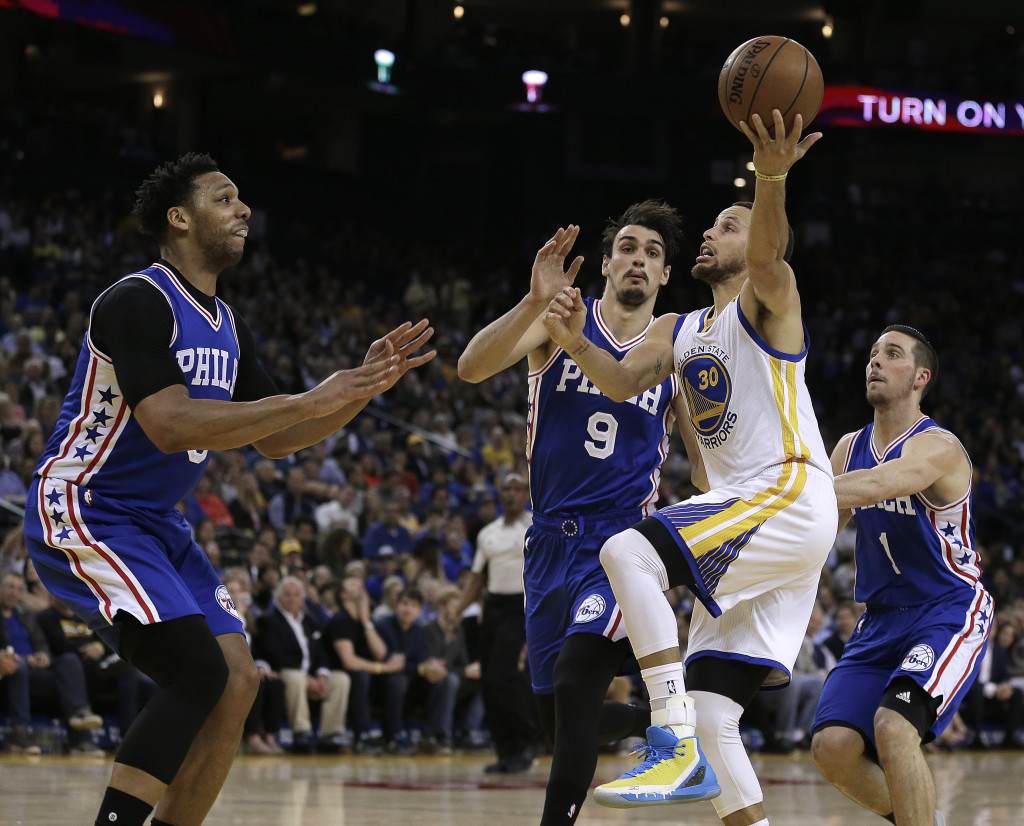 Philadelphia 76ers' Jahlil Okafor, left, Dario Saric (9) and TJ McConnell, right, guard Golden State Warriors' Stephen Curry (30) during the second half of an NBA basketball game Tuesday, March 14, 2017, in Oakland, Calif. Warriors won, 106-104. (AP Photo/Ben Margot)