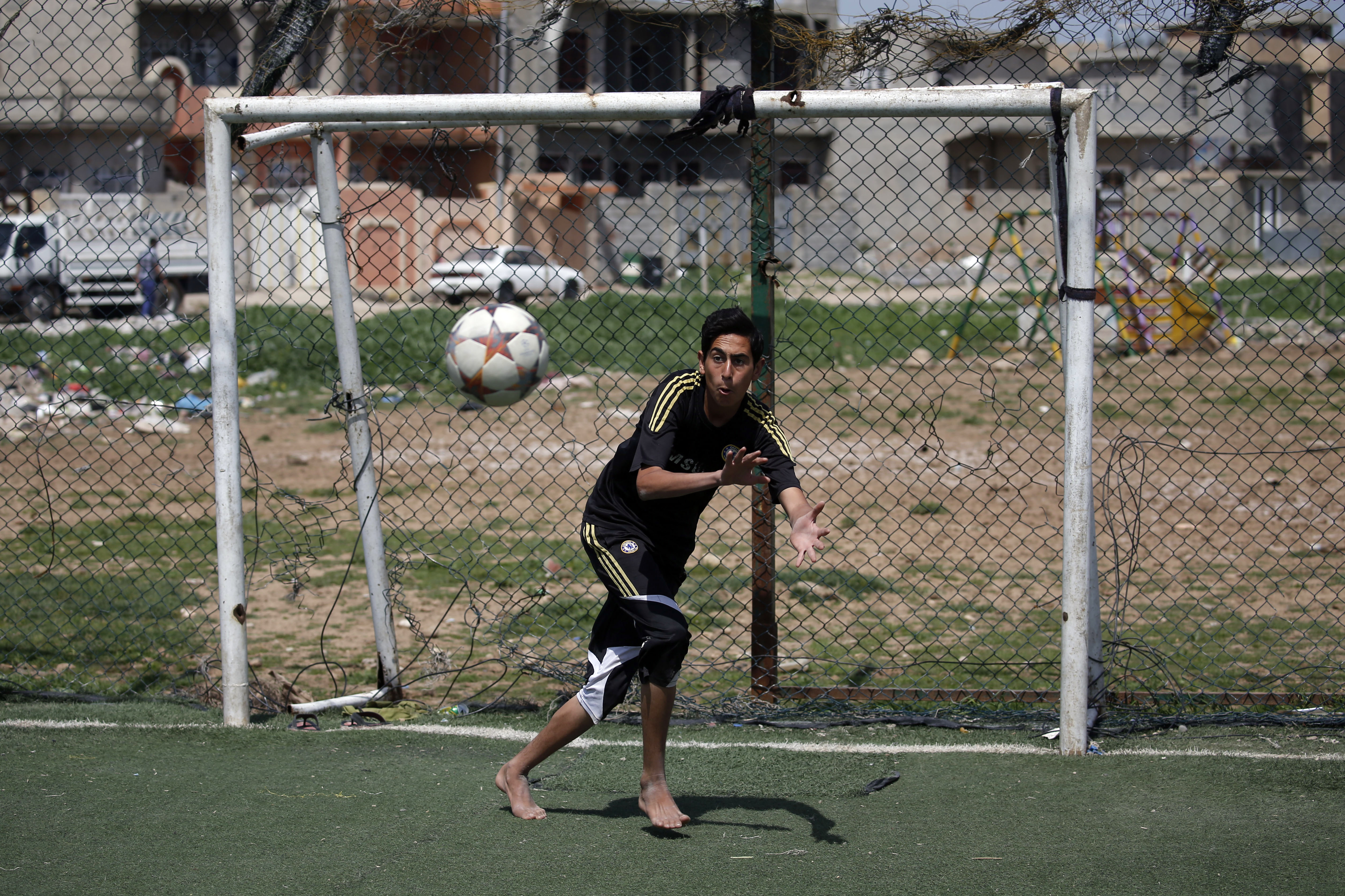 A goalkeeper attempts to stop a shot during a football match in eastern Mosul's al-Salam neighbourhood on April 7, 2017. It was a grim time for football: jihadists observed matches, jerseys from foreign teams were banned and even whistling was prohibited when the Islamic State group held Iraq's Mosul. / AFP PHOTO / AHMAD GHARABLI