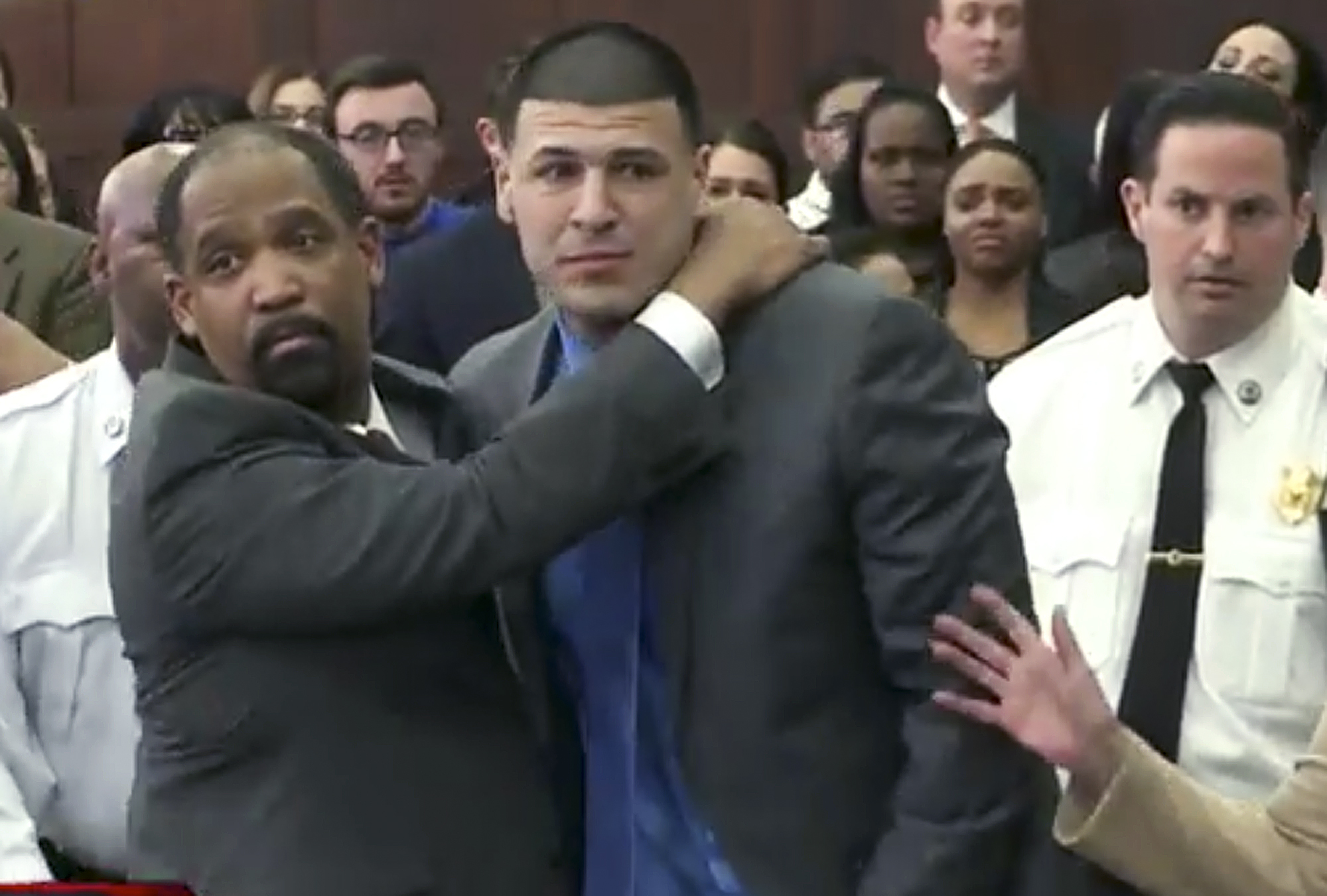 In this still image from video, Aaron Hernandez, center, is hugged by defense attorney Ronald Sullivan Friday, April 14, 2017, in court in Boston, after being found not guilty of murder in the 2012 shootings of two men in a drive-by shooting in Boston. (WHDH-TV via AP, Pool)