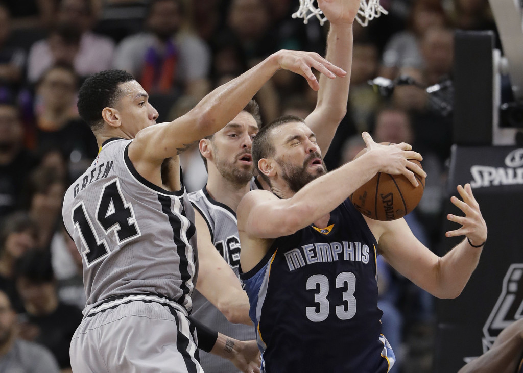 In this April 15, 2017, file photo, Memphis Grizzlies center Marc Gasol (33) is defended by San Antonio Spurs guard Danny Green (14) and center Pau Gasol during the second half in Game 1 of a first-round NBA basketball playoff series, in San Antonio. Pau and Marc Gasol have been battling each other on a basketball court since they were children with the older brother always finding ways to win. Now little brother Marc is doing his best to rally the Grizzlies to avoid being swept away in their first playoff meeting.  (AP Photo/Eric Gay, File)