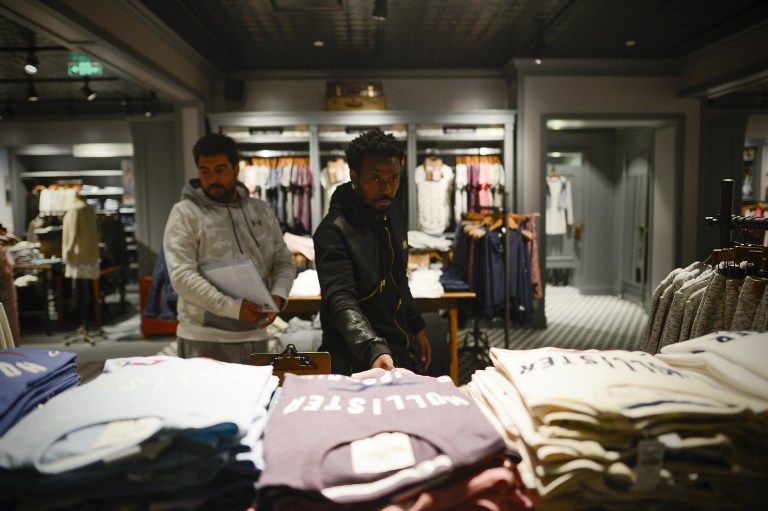 This picture taken on February 22, 2017 shows Chongqing Dangdai Lifan footballer Fernandinho (R) selecting clothes at a store in southwest China's Chongqing Municipality. Fernandinho, one of the growing number of Brazilian footballers in China, is bridging a wide cultural gap and finding celebrity in the southwestern city of Chongqing. / AFP PHOTO / WANG ZHAO