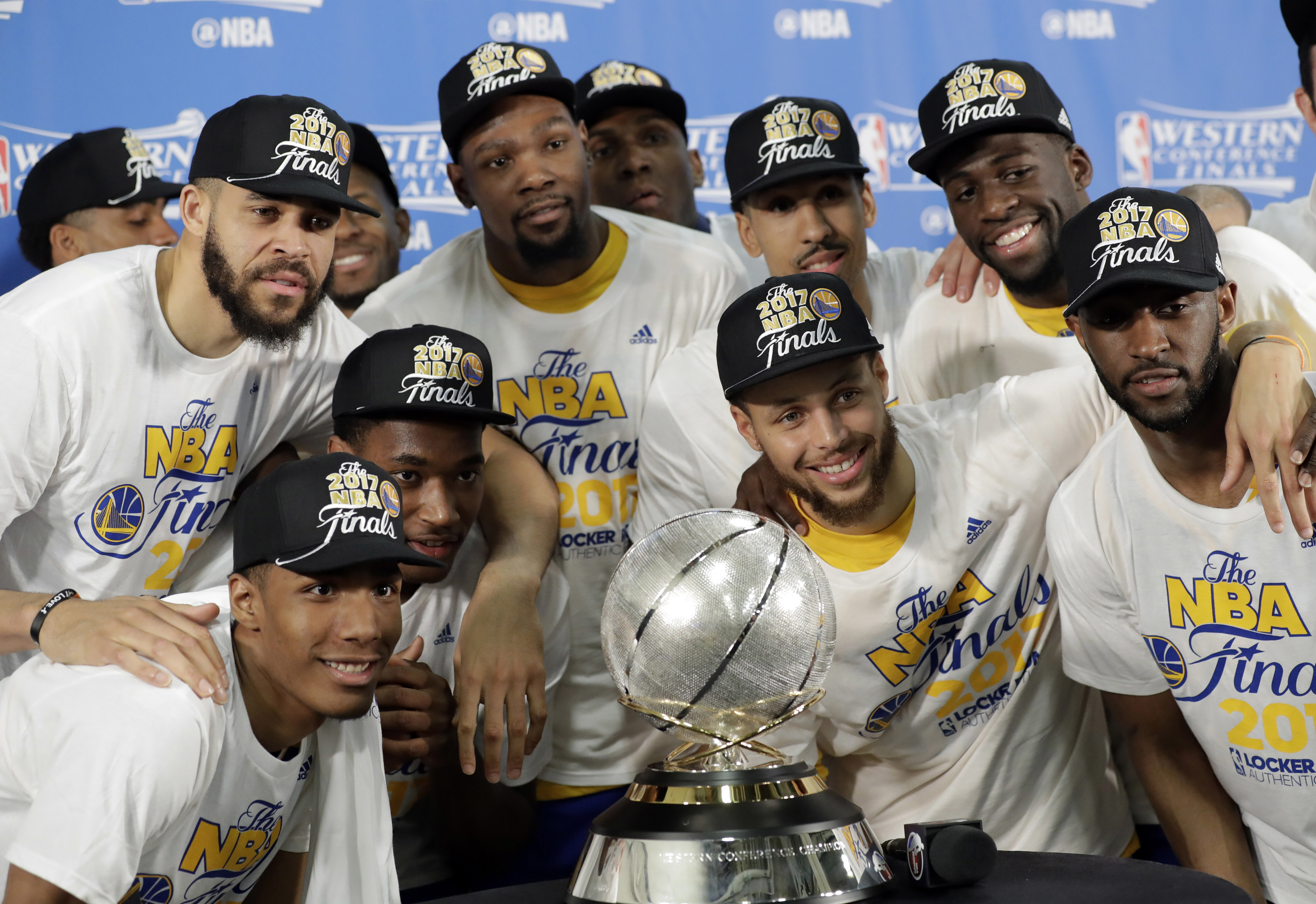 Golden State Warriors' JaVale McGee, top left, Kevin Durant, top center, Stephen Curry, center right, and Draymond Green, top right, join the rest of their team as they pose with the trophy after their 129-115 win over the San Antonio Spurs in Game 4 of the NBA basketball Western Conference finals, Monday, May 22, 2017, in San Antonio. (AP Photo/Eric Gay)