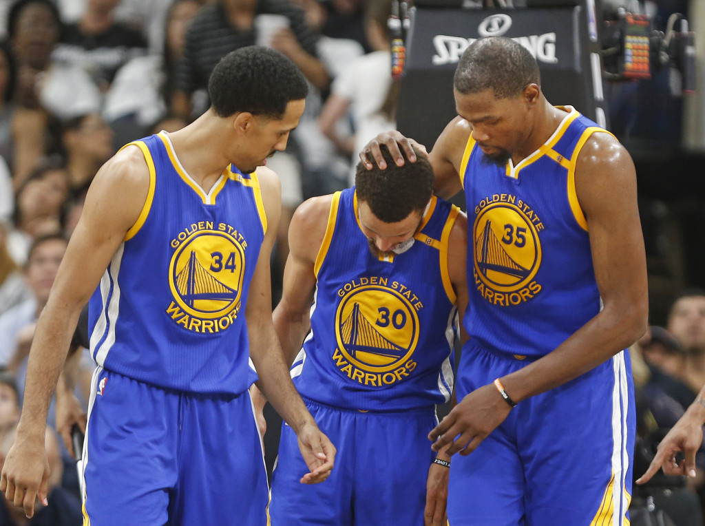 Golden State Warriors forward Kevin Durant (35) comes to the assistance of teammate Golden State Warriors guard Stephen Curry (30) after he was fouled during the second half in Game 3 of the NBA basketball Western Conference finals on Saturday, May 20, 2017, in San Antonio. On the left watching is Golden State Warriors guard Shaun Livingston (34). (AP Photo/Ronald Cortes)