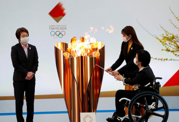 Tokyo 2020 President Seiko Hashimoto looks on as actor Satomi Hishihara and Paralympian Aki Taguchi light the celebration cauldron on the first day of the Tokyo 2020 Olympic torch relay in Naraha, Fukushima prefecture, Japan March 25, 2021.
