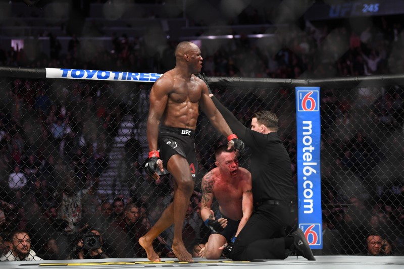Kamaru Usman (red gloves) reacts as referee Marc Goddard stops his bout against Colby Covington