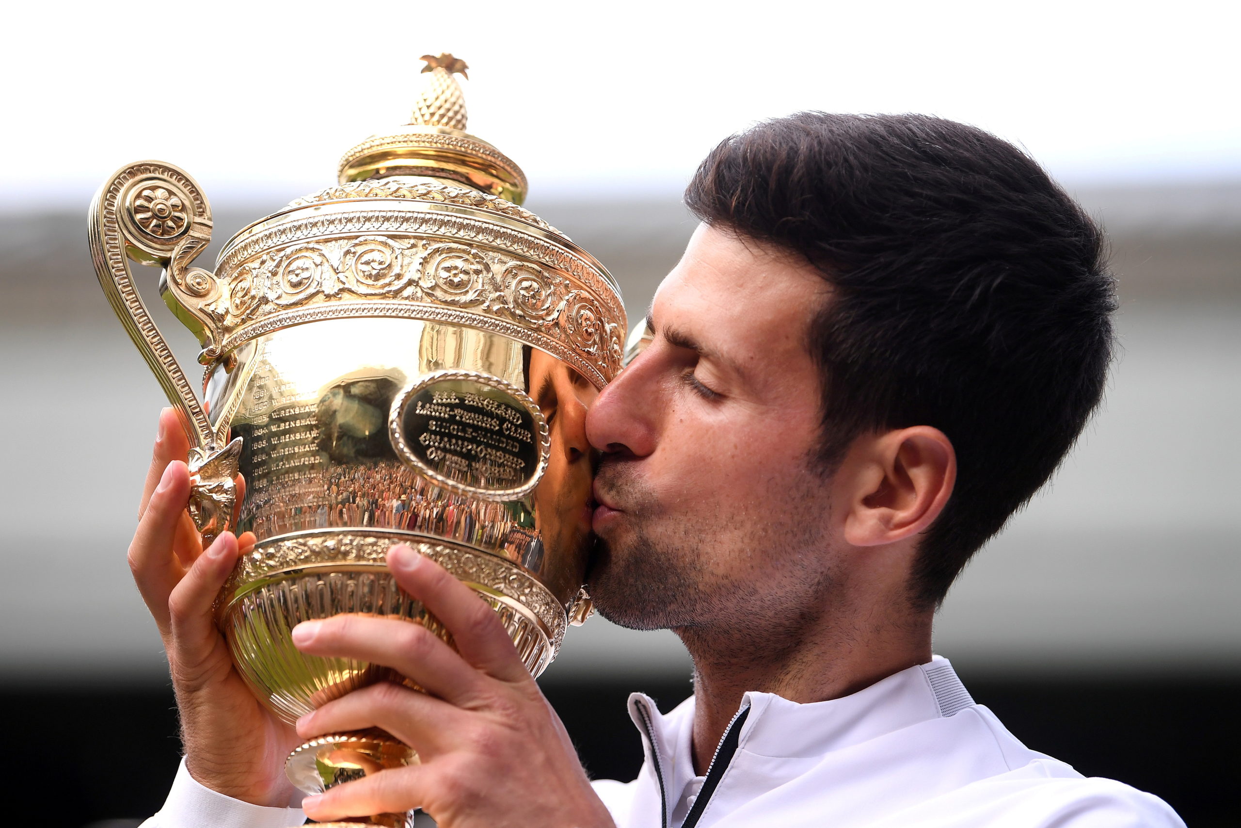 Serbia's Novak Djokovic kisses the trophy as he poses for photographs after winning the Wimbledon final against Switzerland's Roger Federer on July 14, 2019. 