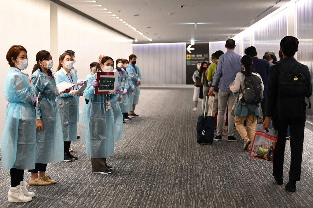 Airport operations crew for the Tokyo 2020 (L) wait for Olympic athletes and officials arriving on a flight from Doha at Narita international airport in Narita, Chiba prefecture on July 14, 2021. 