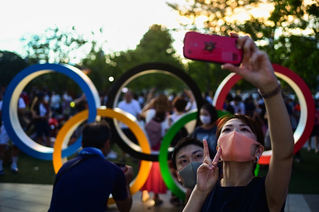 Fans take a selfie in front of the Olympic Rings outside the Olympic Stadium ahead of the opening ceremony of the Tokyo 2020 Olympic Games, in Tokyo, on July 23, 2021.