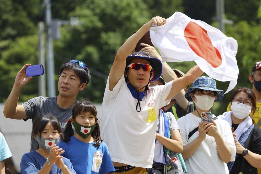 Fans watch cyclist (unseen) ride during the men's cycling road race of the Tokyo 2020 Olympic Games finishing at the Fuji International Speedway in Oyama, Japan, on July 24, 2021. 