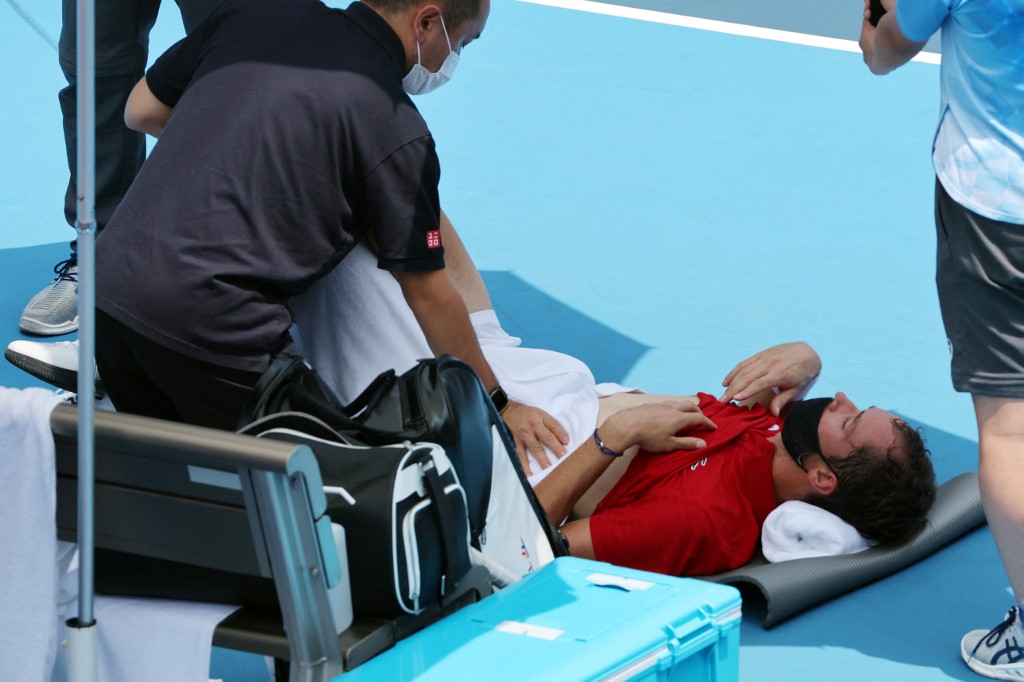 Russia's Daniil Medvedev is assisted by a physio during Tokyo 2020 Olympic Games men's singles third round tennis match against Italy's Fabio Fognini at the Ariake Tennis Park in Tokyo on July 28, 2021.