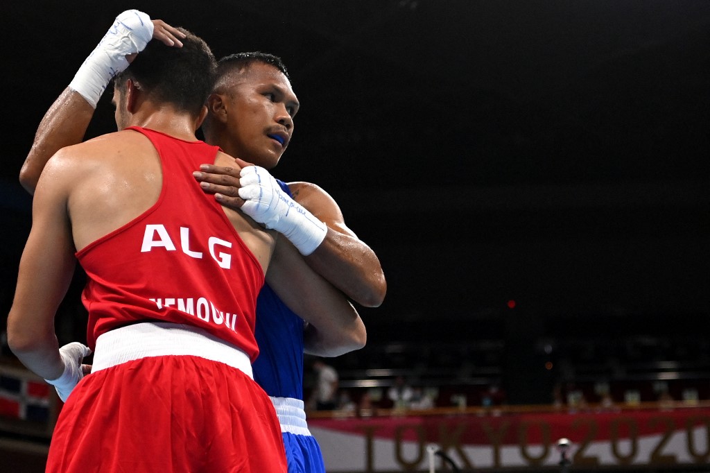 Algeria's Younes Nemouchi (red) and winner Philippines' Eumir Marcial hug at the end of their men's middle (69-75kg) preliminaries round of 16 boxing match during the Tokyo 2020 Olympic Games at the Kokugikan Arena in Tokyo on July 29, 2021. 