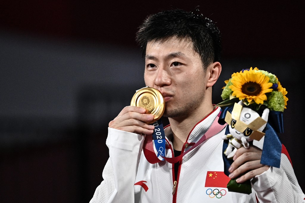 Gold medallist China's Ma Long kisses his medal during the men's singles table tennis medal ceremony at the Tokyo Metropolitan Gymnasium during the Tokyo 2020 Olympic Games in Tokyo on July 30, 2021. (