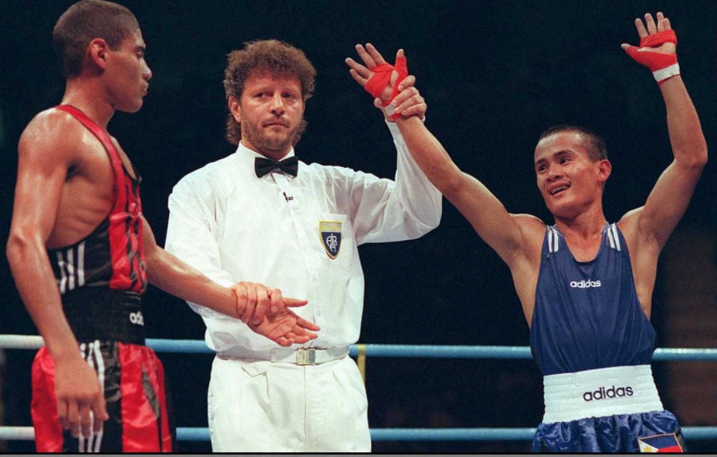 Referee Imre Nagy of Hungary signals that Mansueto Velasco (R) of the Philippines has defeated Yosuani Aguilera of Cuba in their Olympic 48kg bout 26 July.