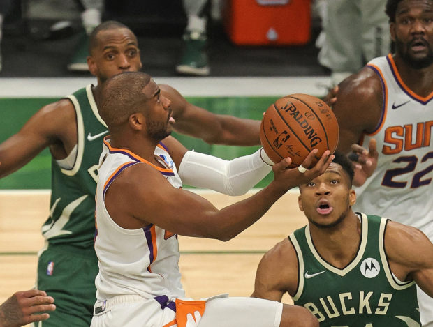 Chris Paul #3 of the Phoenix Suns drives to he basket against Giannis Antetokounmpo #34 and Khris Middleton #22 of the Milwaukee Bucks at Fiserv Forum on July 11, 2021 in Milwaukee, Wisconsin. The Bucks defeated the Suns 120-100. 