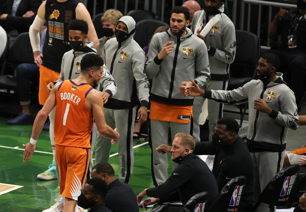 Devin Booker #1 of the Phoenix Suns is greeted by teammates as he goes to the bench during the second half in Game Four of the NBA Finals against the Milwaukee Bucks at Fiserv Forum on July 14, 2021 in Milwaukee, Wisconsin.