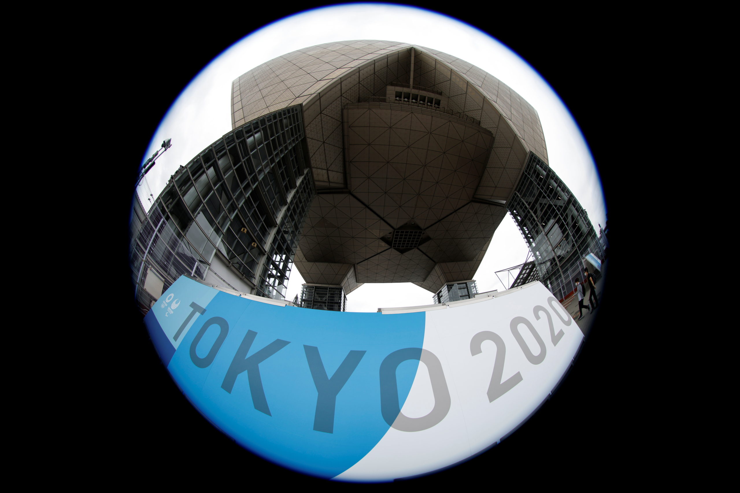 People walk past a sign for the 2020 Tokyo Olympic Games that have been postponed to 2021 due to the coronavirus disease (COVID-19) pandemic, at the IBC/MPC media center at Tokyo Big Sight exhibition center in Tokyo, Japan