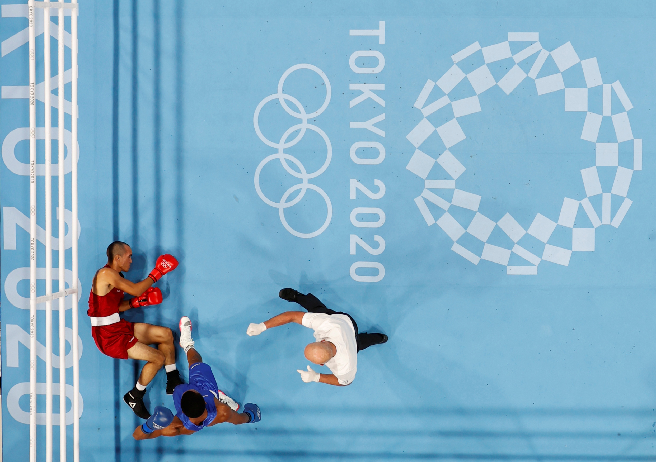 Tokyo 2020 Olympics - Boxing - Men's Middleweight - Last 32 - Kokugikan Arena - Tokyo, Japan - July 26, 2021. Eldric Sella Rodriguez of the Refugee Olympic Team lies on the ground after being knocked down during his fight against Euri Cedeno Martinez of the Dominican Republic