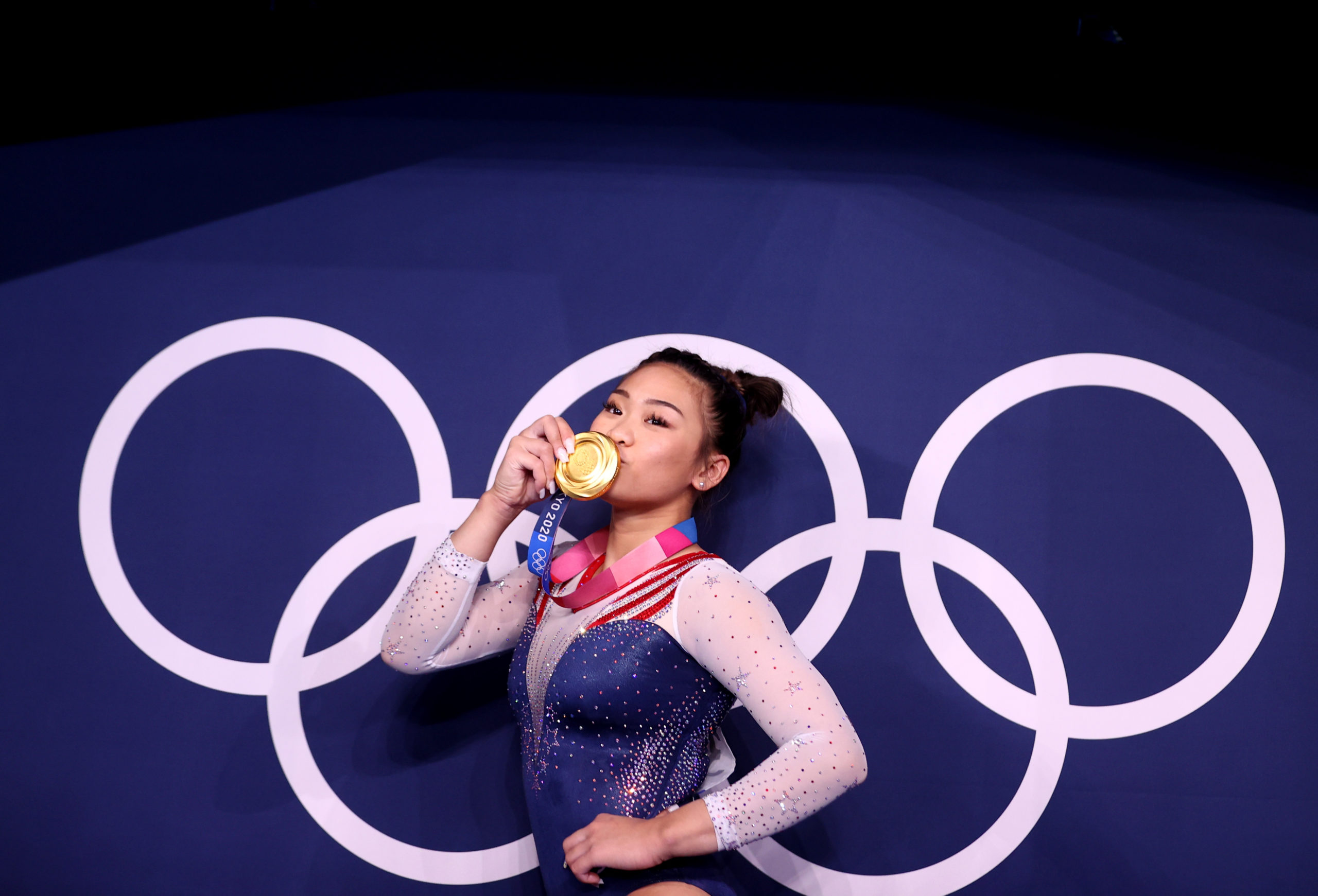 Gold medallist Sunisa Lee of the United States kisses her medal in front of the olympic rings 