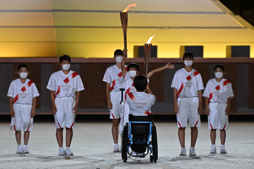 Japanese Paralympic athlete Wakako Tsuchida relays the torch with the Olympic flame to school children during the opening ceremony of the Tokyo 2020 Olympic Games, at the Olympic Stadium, in Tokyo, on July 23, 2021.