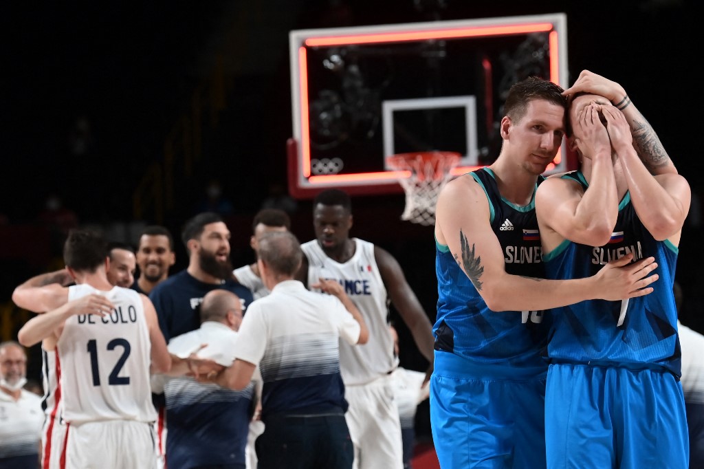 French team members celebrate their win as Slovenia's players (R) react after the men's semi-final basketball match between France and Slovenia during the Tokyo 2020 Olympic Games at the Saitama Super Arena in Saitama on August 5, 2021.