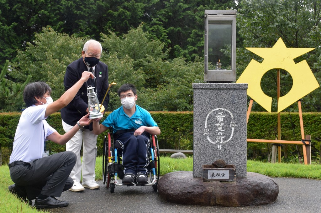 Torchbearer Miu Takahashi (C) lights a lantern during a flame-lighting ceremony for the upcoming Tokyo 2020 Paralympic Games in Rikuzentakata, Iwate prefecture on August 12, 2021. 