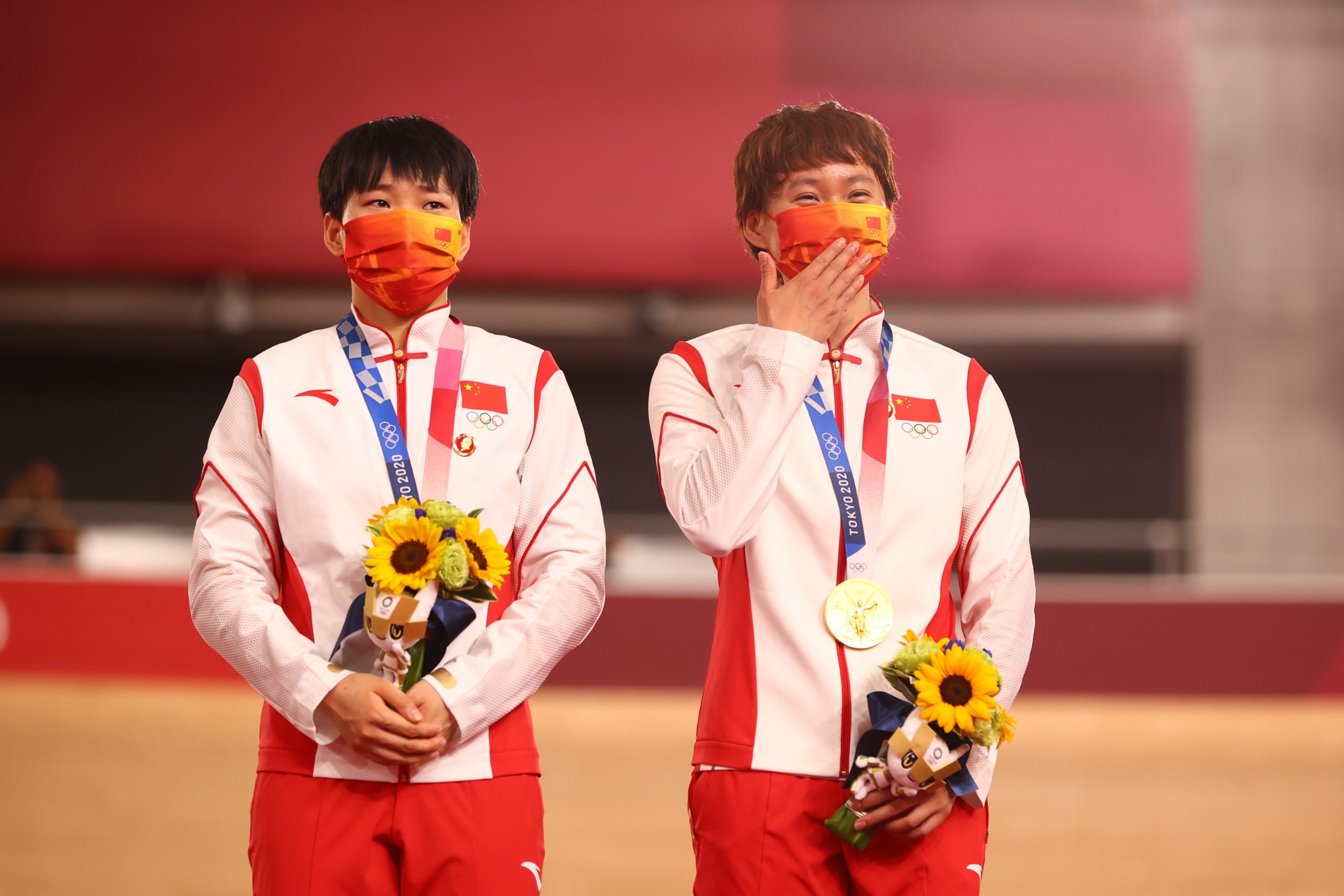 Gold medalists Bao Shanju and Zhong Tianshi of China wearing protective face masks pose with badges of the late Chinese chairman Mao Zedong pinned to their tracksuits. REUTERS/Matthew Childs