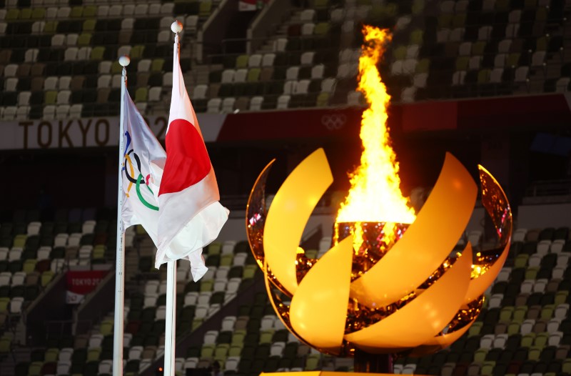 Tokyo 2020 Olympics - The Tokyo 2020 Olympics Opening Ceremony - Olympic Stadium, Tokyo, Japan - July 23, 2021. The Olympic flame is seen lit in the cauldron at the opening ceremony alongside a flag of Japan and the Olympic flag REUTERS/Kai Pfaffenbach
