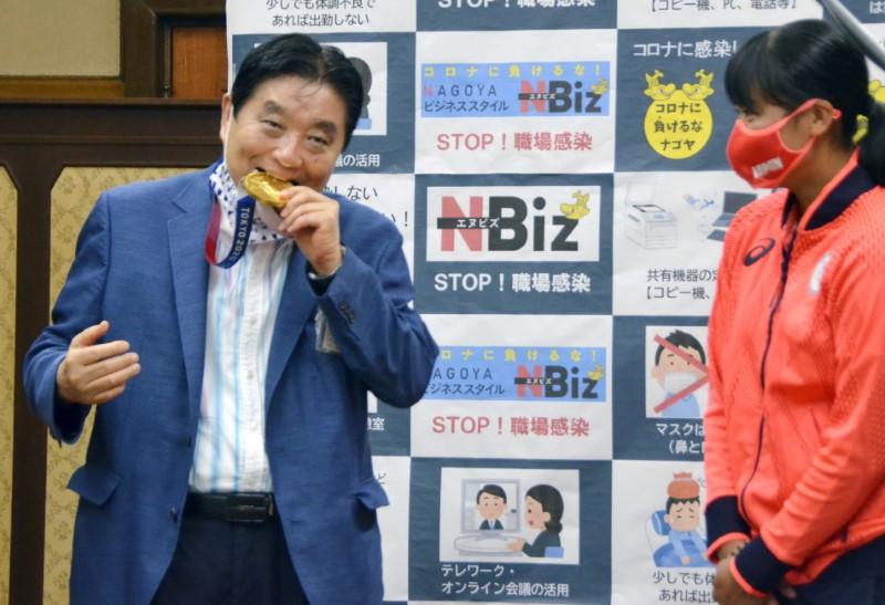  Nagoya city Mayor Takashi Kawamura bites the Tokyo 2020 Olympic Games gold medal of the softball athlete Miu Goto during a ceremony in Nagoya, central Japan, August 4, 2021, in this photo taken by Kyodo.