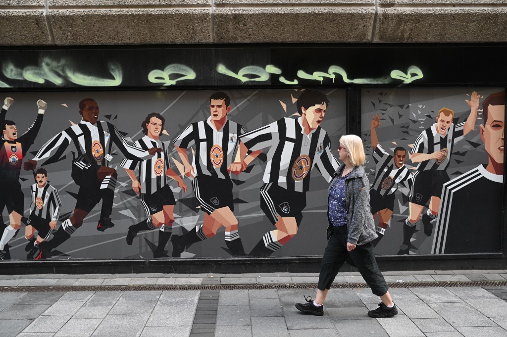 A pedestrian passes a Newcastle United football club-themed mural in Newcastle upon Tyne in northeast England on October 8, 2021. - A Saudi-led consortium completed its takeover of Premier League club Newcastle United on October 7 despite warnings from Amnesty International that the deal represented "sportswashing" of the Gulf kingdom's human rights record. (Photo by Oli SCARFF / AFP)