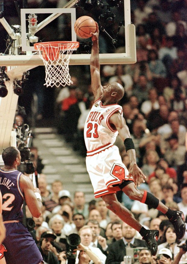 Michael Jordan (R) of the Chicago Bulls flies in for the dunk while Karl Malone (L) of the Utah Jazz watches 10 June during game four of the NBA Finals at the United Center in Chicago, IL. Jordan finished with 34 points as the Bulls beat the Jazz 86-82 to lead the best-of-seven series 3-1. AFP PHOTO/Jeff HAYNES (Photo by JEFF HAYNES / AFP)