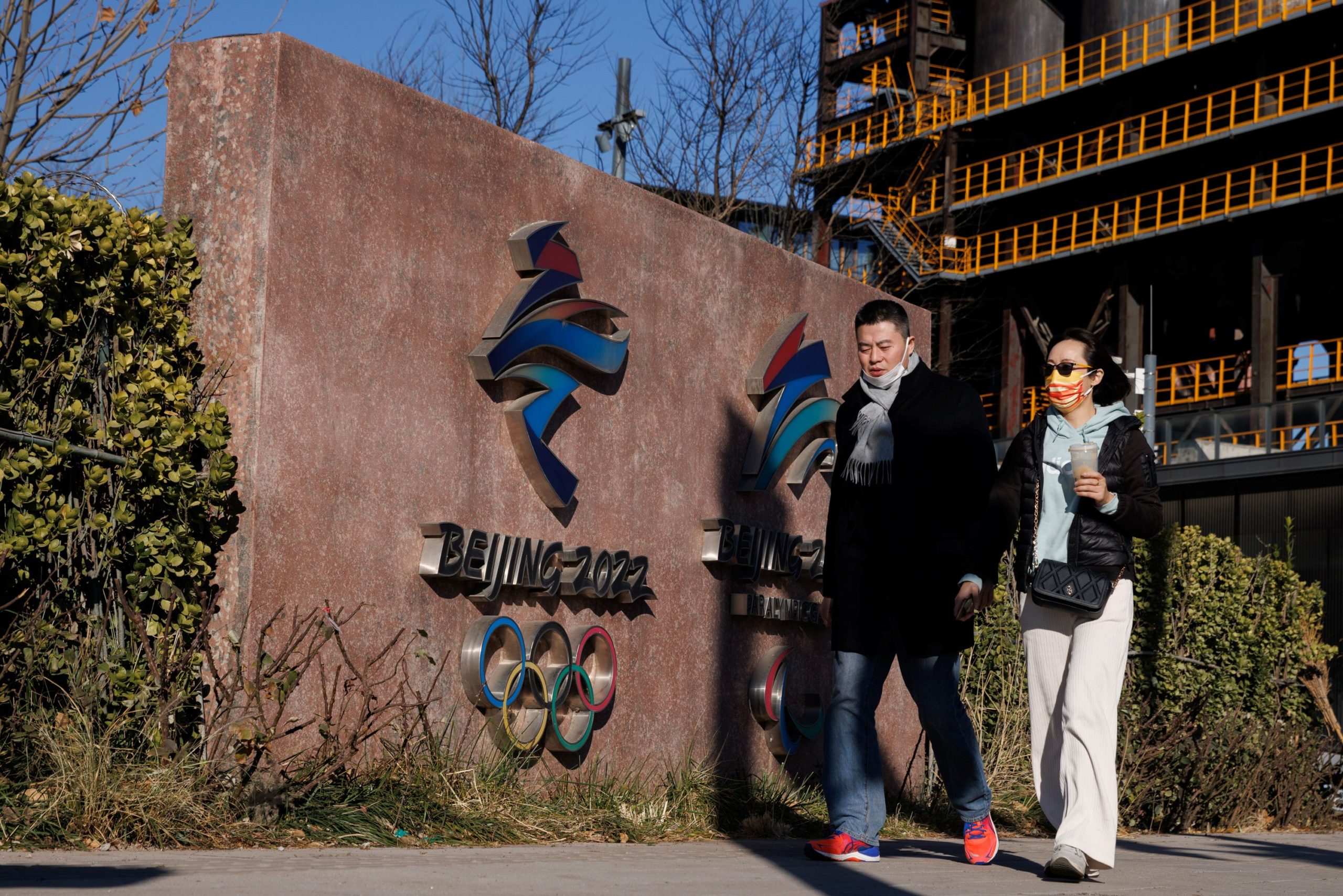 People walk past the headquarters of the Beijing Organizing Committee for the 2022 Olympic and Paralympic Winter Games in Shougang Park, the site of a a former steel mill, in Beijing, China, November 30, 2021. 