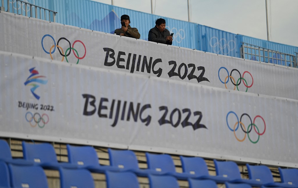 Men use their mobile phones at the spectator area of the Shougang Big Air venue, which will host the big air freestyle skiing and snowboarding competitions at the Beijing 2022 Winter Olympics, at the Shougang Park in Beijing on December 15, 2021.