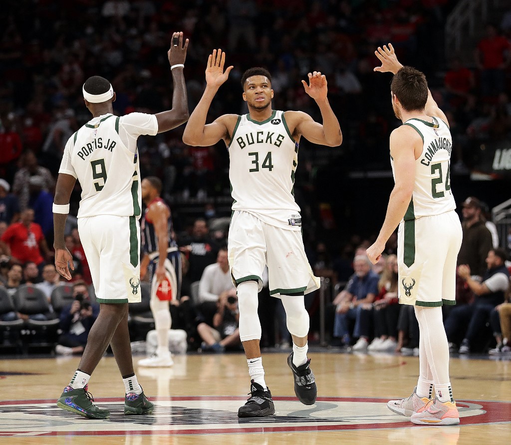 Giannis Antetokounmpo #34 of the Milwaukee Bucks receives high fives from Pat Connaughton #24 of the Milwaukee Bucks and Bobby Portis #9 after a fast break dunk during the fourth quarter against the Houston Rockets at Toyota Center on December 10, 2021 in Houston, Texas.