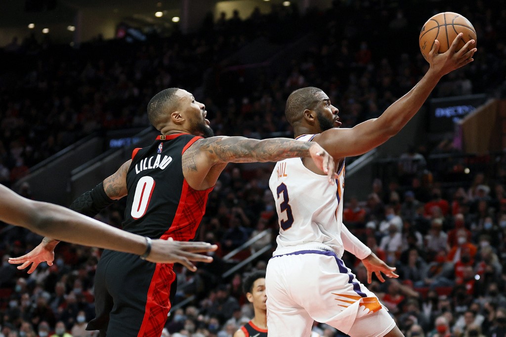 Chris Paul #3 of the Phoenix Suns drives to the basket against Damian Lillard #0 of the Portland Trail Blazers during the fourth quarter at Moda Center on December 14, 2021 in Portland, Oregon.
