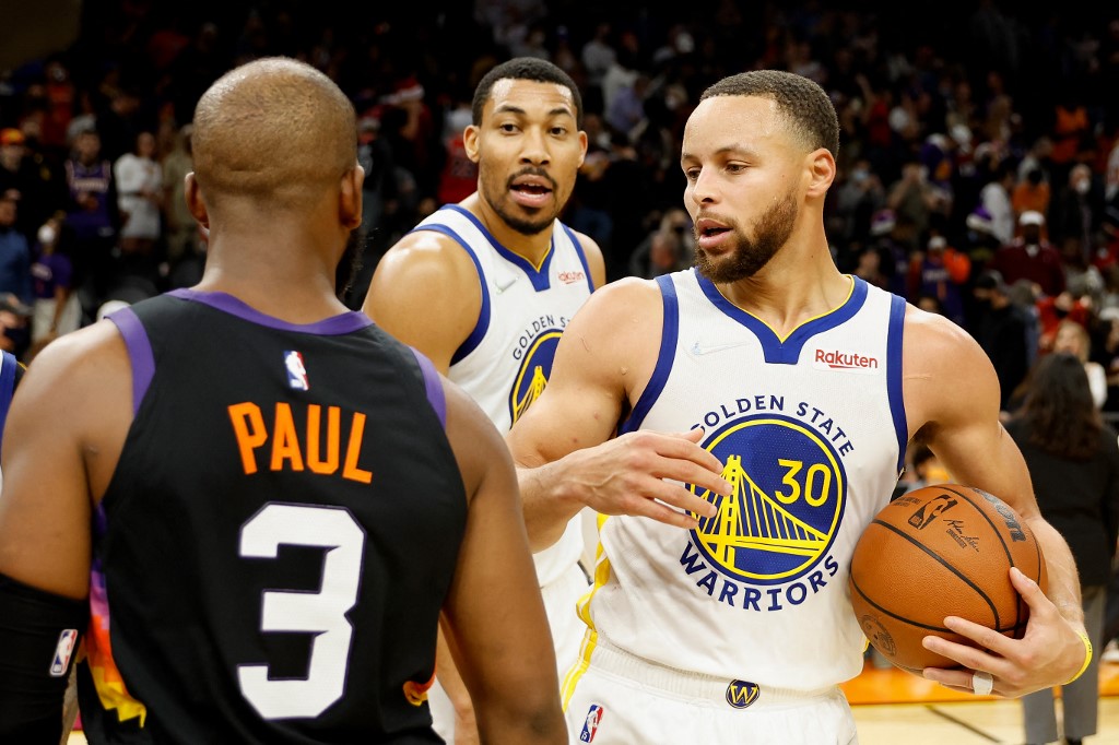 Stephen Curry #30 and Otto Porter Jr. #32 of the Golden State Warriors greet Chris Paul #3 of the Phoenix Suns following the NBA game at Footprint Center on December 25, 2021 in Phoenix, Arizona. The 